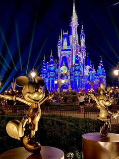 mickey mouse statue in front of the castle at night