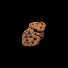 three chocolate chip cookies are stacked on top of each other in front of a black background