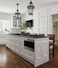 a large kitchen with white cabinets and black counter tops, along with an island in the middle