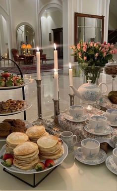 a table topped with plates and cups filled with desserts next to tall vases