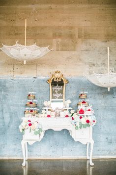 a white table topped with a mirror next to a wall covered in lace and flowers