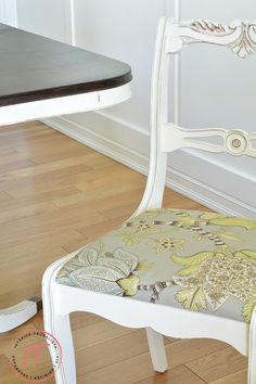 a white chair sitting next to a wooden table on top of a hard wood floor