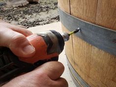 a man is using a drill to fix a wooden barrel with a screwdriver