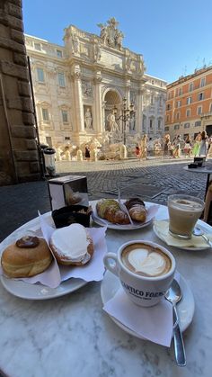 a table topped with plates of food next to a cup of cappuccino