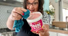 a woman holding up a cup of pink stuff