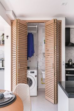 an open door leading to a washer and dryer in a room with white walls