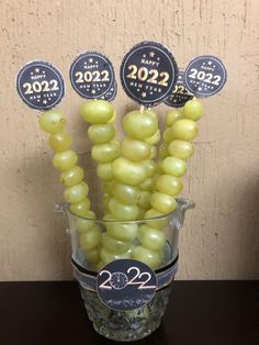 some grapes are in a glass vase on a table with two new year's stickers