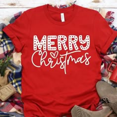 a red shirt that says merry christmas with white letters on it, surrounded by plaid fabric