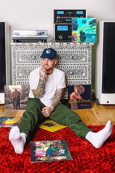 a man sitting on the floor with his feet up in front of him, surrounded by books