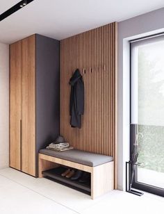 a room with a bench, coat rack and sliding glass door that opens to the outside