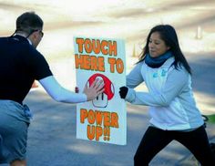 a man and woman holding up a sign that says, touch here to power up