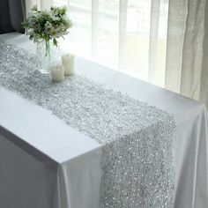 a white table cloth with silver sequins on it and two candles next to it