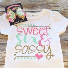 a t - shirt with the words sweet and sassy on it, sitting on a wooden surface