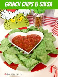 a heart shaped bowl filled with salsa surrounded by tortilla chips