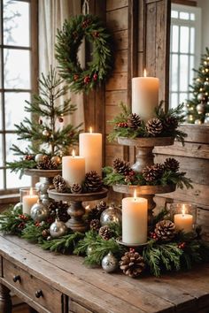 a table topped with lots of candles next to christmas wreaths and pineconis