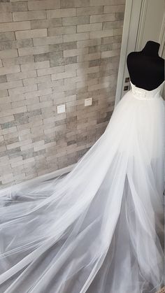 a white wedding dress on display in front of a brick wall