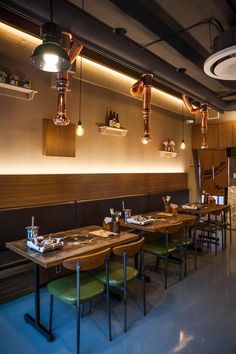 an empty restaurant with wooden tables and green chairs in front of the counter, along with hanging lights