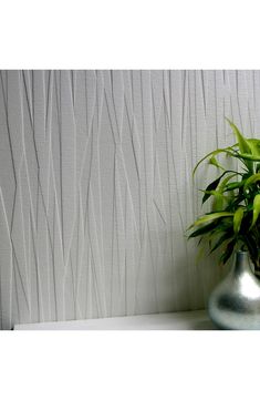 a potted plant sitting on top of a white shelf next to a wall paper