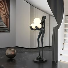 a statue is holding a light in the middle of a room with stairs and white walls