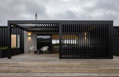 a black house with stairs leading up to the front door and patio area on top of it