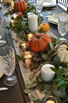 the table is set with candles, pumpkins and greenery for an elegant thanksgiving dinner