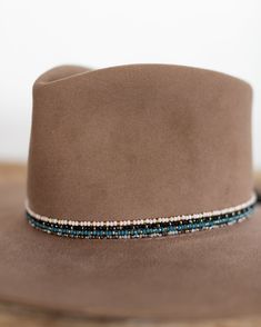 This hat band mixes beautiful faceted glass beads with brass accents to create a subtle sparkle to add to your hat. Material: Faceted glass beads & brass beads Dimensions: 21" beaded length Closure: Adjustable slide closure Color Options: Black, Gray, Beige, Blue Handmade by Crossbow in the mountains of Telluride, CO. Diy Hat Band Ideas, Hatband Beaded, Cowboy Hat Bands Diy, Beaded Hats Native American, Metis Beadwork Patterns, Western Hat Bands, Burned Hats, Cowboy Hat Band, Glass Hat