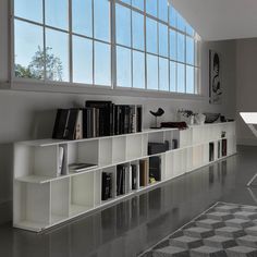 a white book shelf with books on it in front of a large window and checkered rug