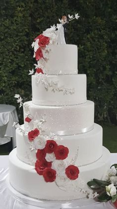 a wedding cake with red and white flowers on it