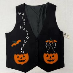 a black vest with two pumpkins and a cat on it