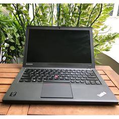 an open laptop computer sitting on top of a wooden table next to a potted plant