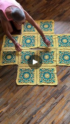 a woman is working on a crocheted rug in the middle of a wood floor