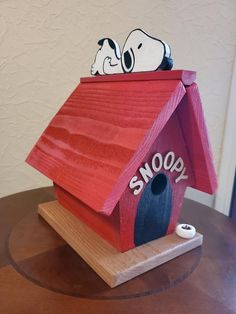 a wooden birdhouse with snoopy painted on it