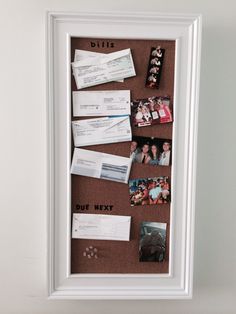 a bulletin board with photos, mail and other items on it in a white frame