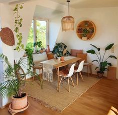 a living room filled with lots of plants next to a wooden table and white walls