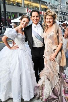 two women and a man in formal wear posing for the camera on a street corner