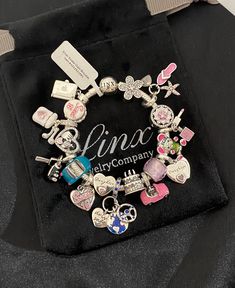 a bracelet with charms on it sitting on top of a black cloth covered case,