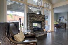 a living room with a couch, chair and fire place inside of it on top of hard wood flooring