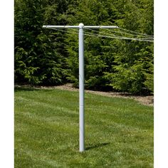 an electric pole in the middle of a grassy area with trees and bushes behind it