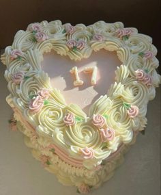 a heart shaped cake with pink and white frosting in the shape of a 1