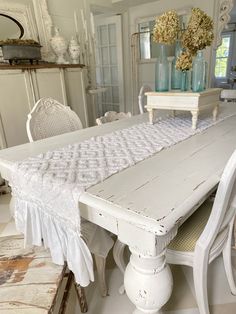 an old white table and chairs in a room with antique furniture on the floor,