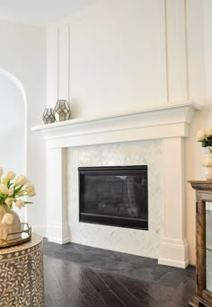 a living room with a fire place and vases on top of the fireplace mantel