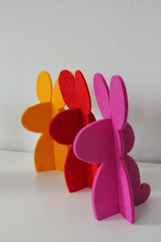 three different colored paper sculptures sitting next to each other on a white counter top,