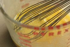 a blender filled with yellow liquid and whisk in it's glass bowl