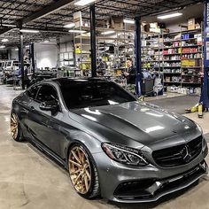 a grey car parked in a garage with gold rims on it's wheels