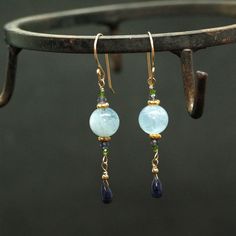 "Moss Aquamarine and natural Blue Sapphire Earrings A natural dark blue Sapphire Briolettes are dangling below large (10mm) Blue Moss Aquamarine beads accented with green Diopside and Iolite beads. The Briolette and the gems are wrapped with high quality 14k gold filled wire and swing from a gold filled hook. These are natural, not colourd excellent AAA quality gems, beautifuly faceted and sparkling. An elegant and feminine, chic statement earrings, perfect for special occasion, wedding, holiday Blue Natural Stones Long Drop Jewelry, Blue Long Drop Jewelry With Natural Stones, Blue Long Drop Natural Stone Jewelry, Blue Aquamarine Drop Jewelry, Blue Gemstone Crystal Drop Earrings, Handmade Blue Aquamarine Earrings, Aquamarine Drop Earrings With Ear Wire, Aquamarine Dangle Earrings With Ear Wire, Blue Gemstone Accented Round Earrings