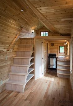 the interior of a tiny house with wood flooring and stairs leading up to an oven