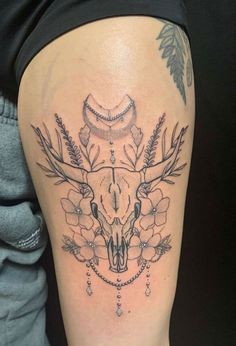 a woman's thigh with a cow skull and flowers on it