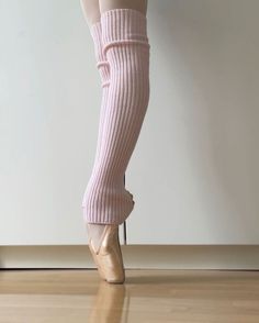 a woman's legs in high heeled shoes and tight socks, standing on a hard wood floor