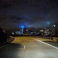 the city lights shine brightly in the night sky from an empty highway with no traffic