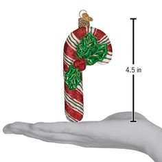 a hand holding an ornament in the shape of a candy cane